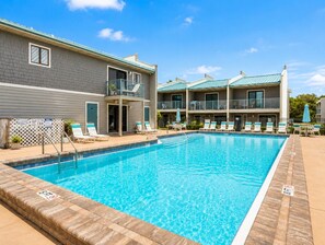 A swimming pool with lounge chairs and a building with balconies. - Gulf Winds East #12 - Pearl of the Sea (Miramar Beach)