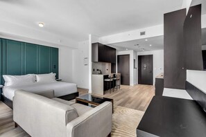 A modern hotel room with a bed, a sofa, a desk, and a kitchenette. - The Signature Eleven and Pool (Miami)