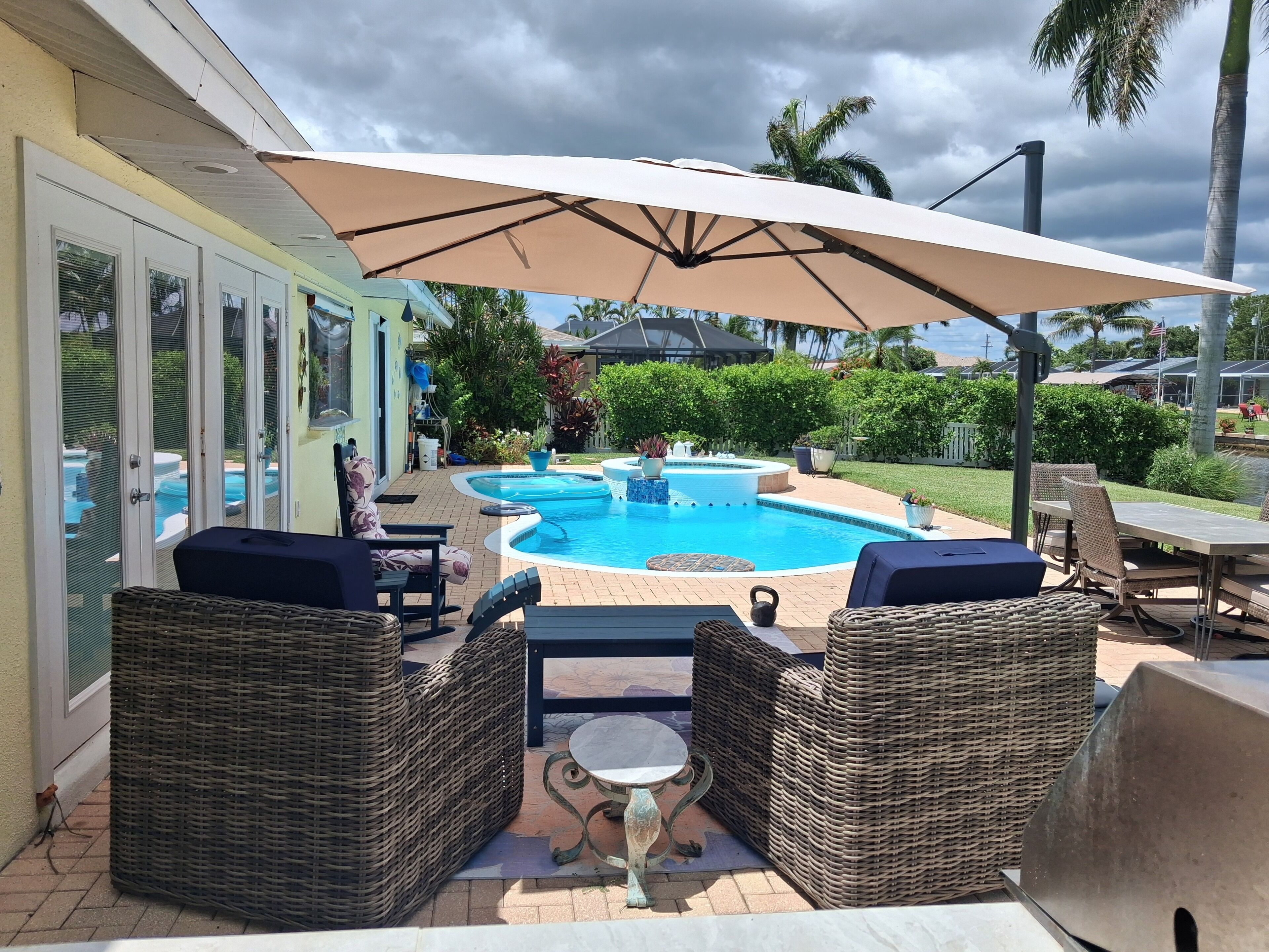 An outdoor pool area with wicker furniture and a covered seating area.