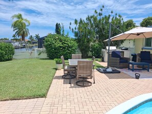 Un jardin avec un espace patio, du mobilier d’extérieur, une piscine et une vue sur un port de plaisance.