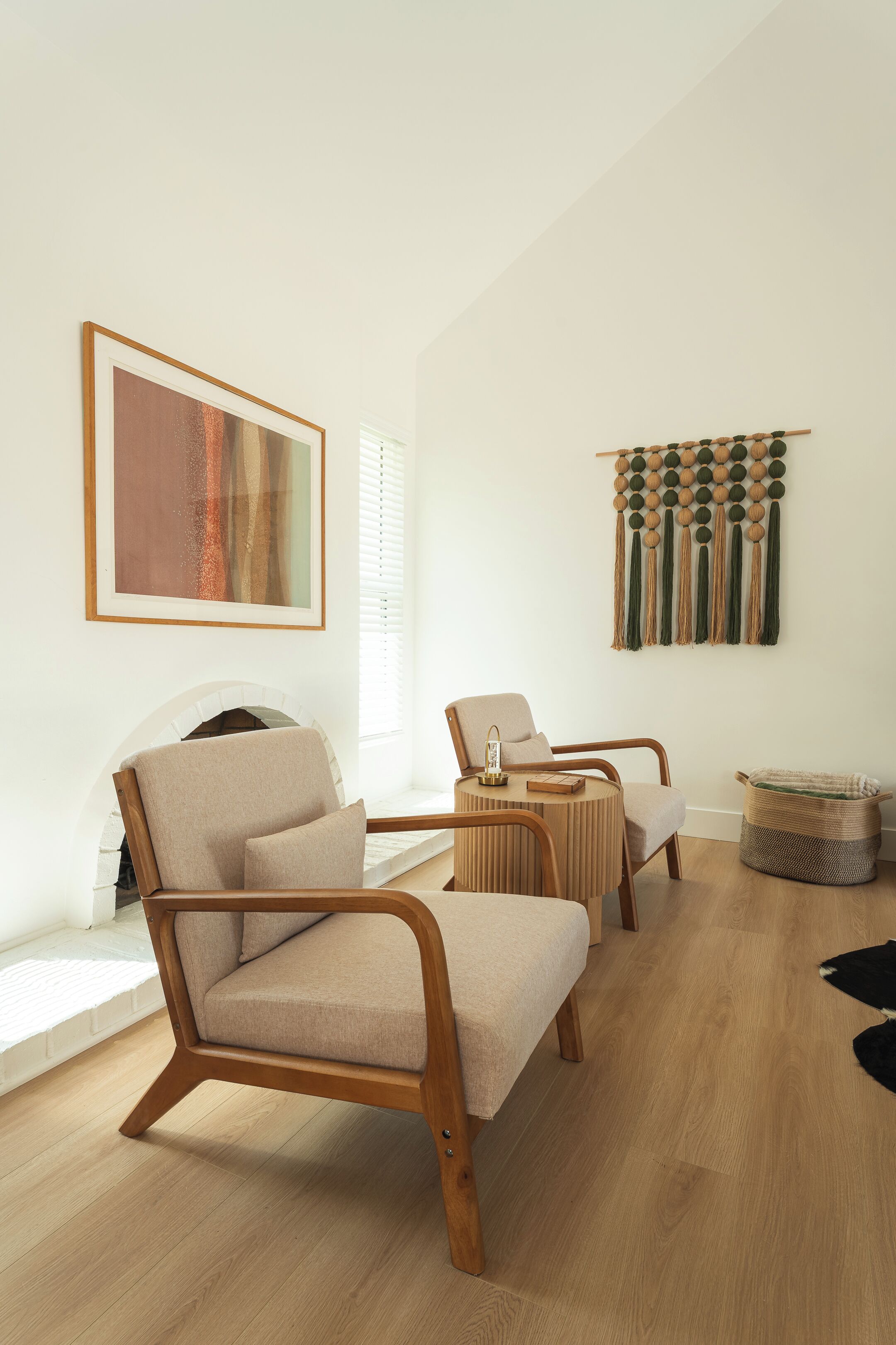 Una sala de estar moderna con un sofá, un sillón y un macramé colgado en la pared.