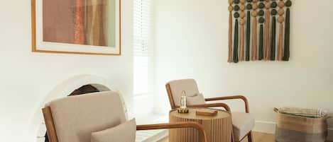 A modern living room with a sofa, armchair, and a wall-mounted macrame piece.