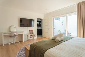 Ein Hotelzimmer mit Bett, Schreibtisch mit Stuhl, Fernseher und einem durchgegangenen Tür sichtbaren Badezimmer.