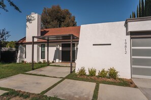 A modern house with a garage, a covered entryway, and a well-maintained lawn. - Luxury Escape, Backyard Pool & Hillside Views (Los Angeles)