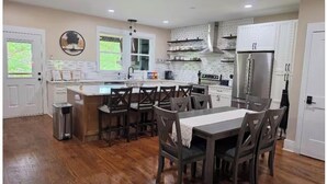 A modern kitchen with a central island, bar stools, and a dining table with chairs. - Escape to a peaceful retreat with breathtaking golf course views in Helen.  (Helen)