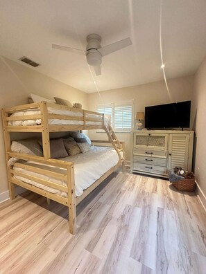 A bunk bed with a ceiling fan, a television, and a cabinet in a room with wooden flooring. - Villa Van Vista Luxury Gulf Access Retreat (Cape Coral)