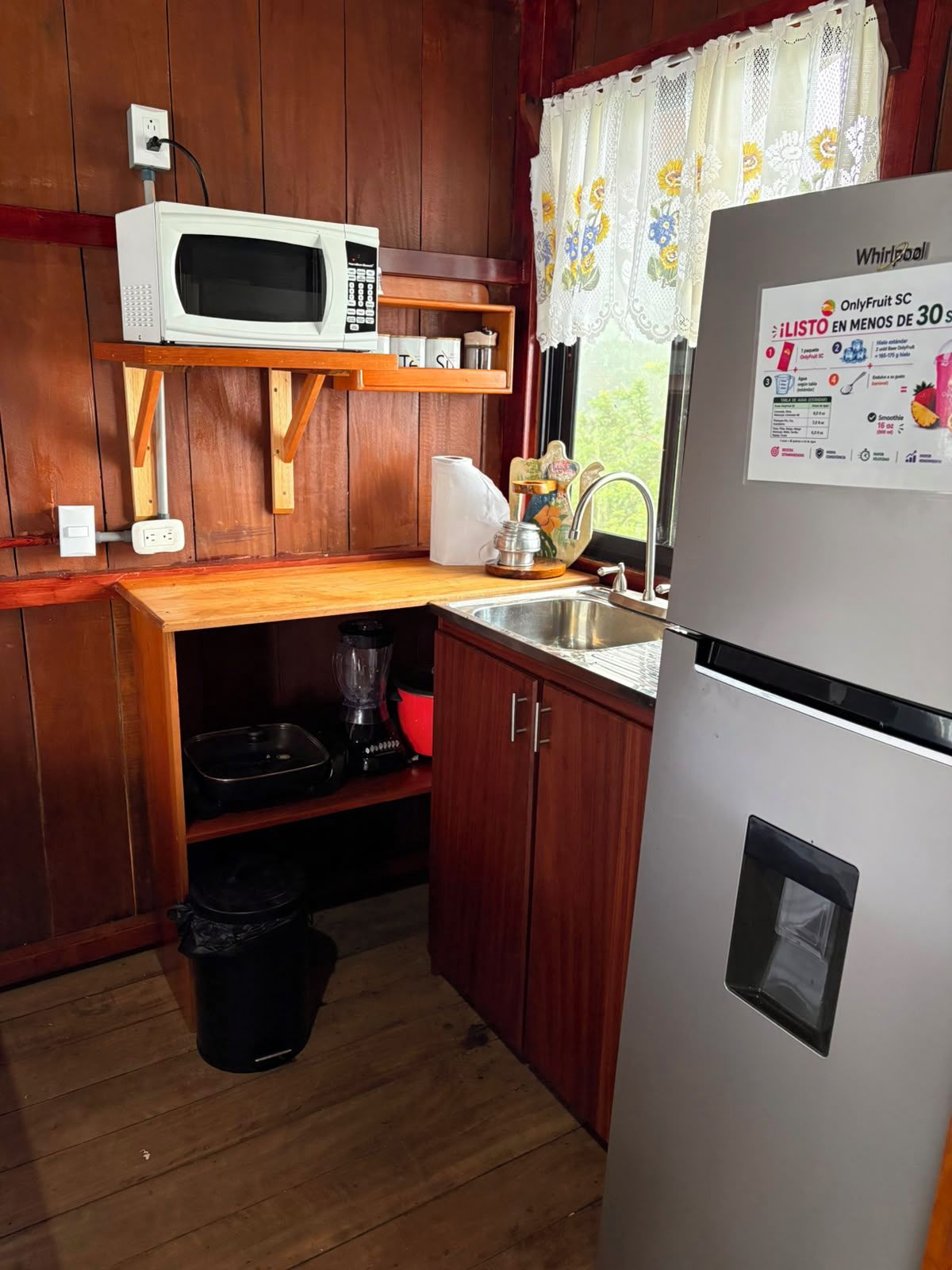 Eine kleine Küche mit Mikrowelle, Kühlschrank, Spüle und Holzschränken.