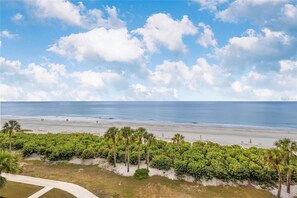 Blick auf einen Strand mit blauem Himmel, Palmen und einem Weg zum Strand.