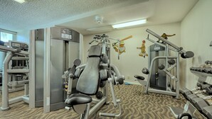 Une salle de sport équipée de divers appareils d’entraînement, notamment une machine pour les jambes, une machine pour les pectoraux et un banc de développé couché.
