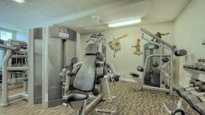 Ein Fitnessstudio mit verschiedenen Trainingsgeräten, darunter eine Beinpresse, eine Brustpresse und eine Hantelbank.