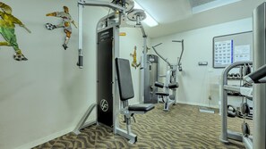 A gym with various exercise machines, a wall-mounted mirror, and a bulletin board with notices. - Stunning Beachfront 2 BR Condo (Longboat Key)