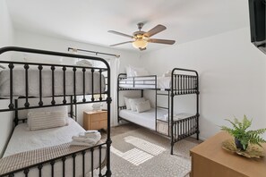 A dormitory room with bunk beds, a ceiling fan, a bedside table, and a small plant. - The Elliott, Ocean Walk Getaway, Pools & Walkable Location (St. Simons Island)