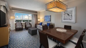 Ein Hotelzimmer mit großem Fenster, Esstisch, Sofagarnitur und Fernseher.