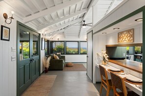 A modern kitchen with a dining area, a sofa, and a view through the window. - 2BR West Maui condo with pool, patio, AC, and full kitchen -ICC 4 (Lahaina)