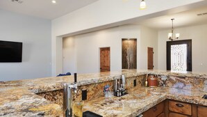Una cucina moderna con piani di lavoro in granito, lavello incassato e rubinetto in acciaio inossidabile.