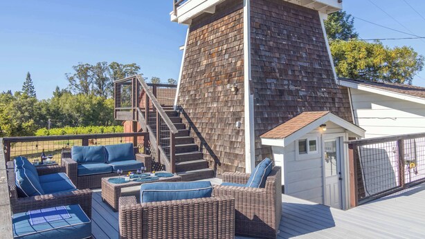 A deck with wicker furniture and a staircase leading to a balcony. - Vineyard Estate & Water Tower | Hot Tub | Views (Sebastopol)