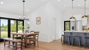A modern kitchen with a wooden dining table, bar stools, and pendant lighting. - Sonoma Retreat w/ Deck, Views & BBQ (Sonoma)