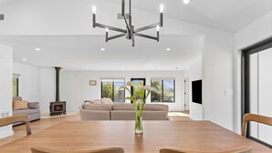 A spacious dining area with a wooden table and chairs, a central vase with flowers, and a modern chandelier. - Sonoma Retreat w/ Deck, Views & BBQ (Sonoma)