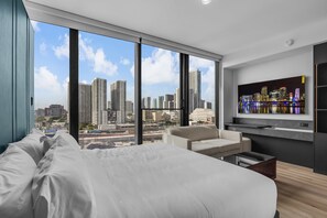 A modern hotel room with a large bed, a sofa, a TV, and a city view. - Magic City & Rooftop Pool (Miami)