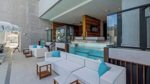 Uma área de estar moderna ao ar livre, com assentos, piscina e vista para a cidade.