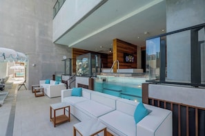 A modern outdoor lounge area with seating, a pool, and a view of the city. - Magic City & Rooftop Pool (Miami)