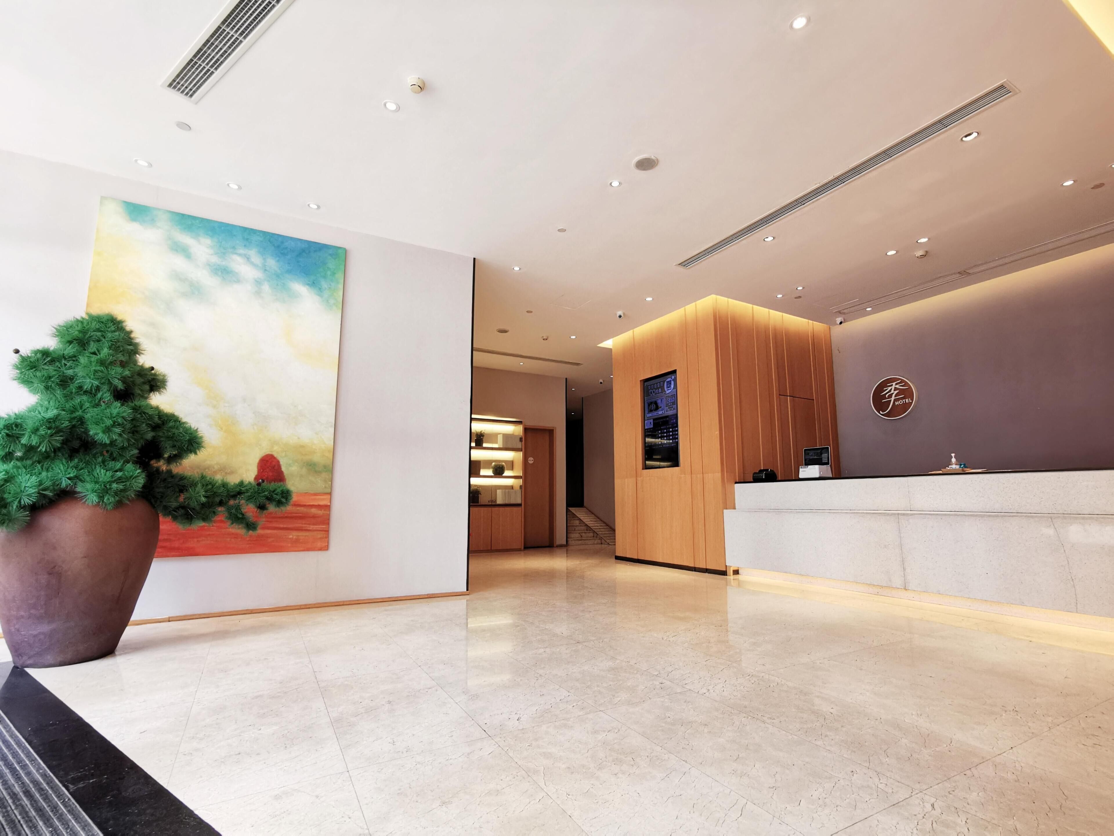 A hotel reception area with a large painting, a reception desk, and a staircase leading to the upper floors.