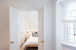 A bedroom with a bed, bedside table, and a window with blinds. - BONDI HAVEN- CHIC 2 BEDROOM APARTMENT (Bondi)