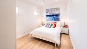 A bedroom with a bed, nightstands, a ceiling fan, a window, and a wall-mounted artwork. - BONDI HAVEN- CHIC 2 BEDROOM APARTMENT (Bondi)
