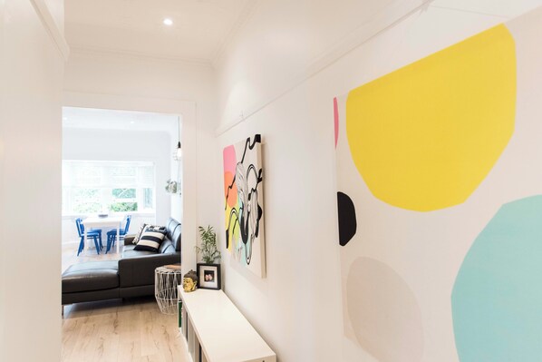 A modern living space with a sofa, a dining area, and a wall with abstract art. - BONDI HAVEN- CHIC 2 BEDROOM APARTMENT (Bondi)