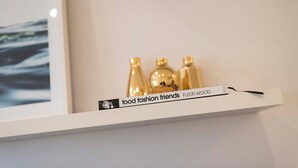 A white shelf with a book titled 'food fashion friends' and a nameplate reading 'FLEUR WOOD' against a plain wall. - BONDI HAVEN- CHIC 2 BEDROOM APARTMENT (Bondi)