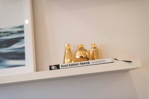 Ein weißes Regal mit einem Buch mit dem Titel 'food fashion friends' und einer Namensschild, auf der 'FLEUR WOOD' steht, vor einer schlichten Wand.