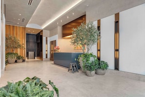 A modern hotel lobby with a reception desk, potted plants, and a signboard. - Miami E11even w Resort Amenities (Miami)