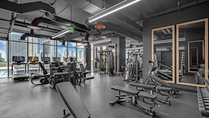 Een moderne sportschool met diverse fitnessapparaten, grote ramen en uitzicht over de stad.