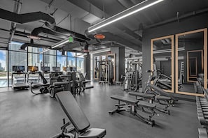 A modern gym with various exercise equipment, large windows, and a city view. - Miami E11even w Resort Amenities (Miami)