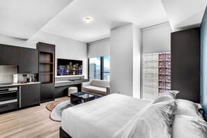 A modern hotel room with a bed, a sofa, a desk, and a large window with a city view. - Miami E11even w Resort Amenities (Miami)