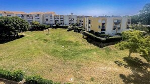 Un edificio residencial con varios balcones, un patio con césped y abundante vegetación.
