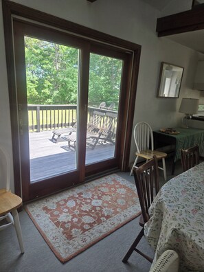 Ein Zimmer mit einer Schiebetür und einem Glasfenster, das auf eine Terrasse mit Stühlen und einem Tisch führt.