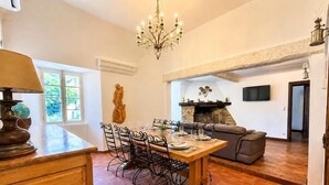 A dining area with a wooden table and chairs, a chandelier, a fireplace, and a sofa. - The House of Observance (DRAGUIGNAN)