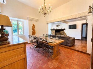 Ein Essbereich mit Holztisch und -stühlen, einer Chandelüster, einem Kamin und einer Couch.