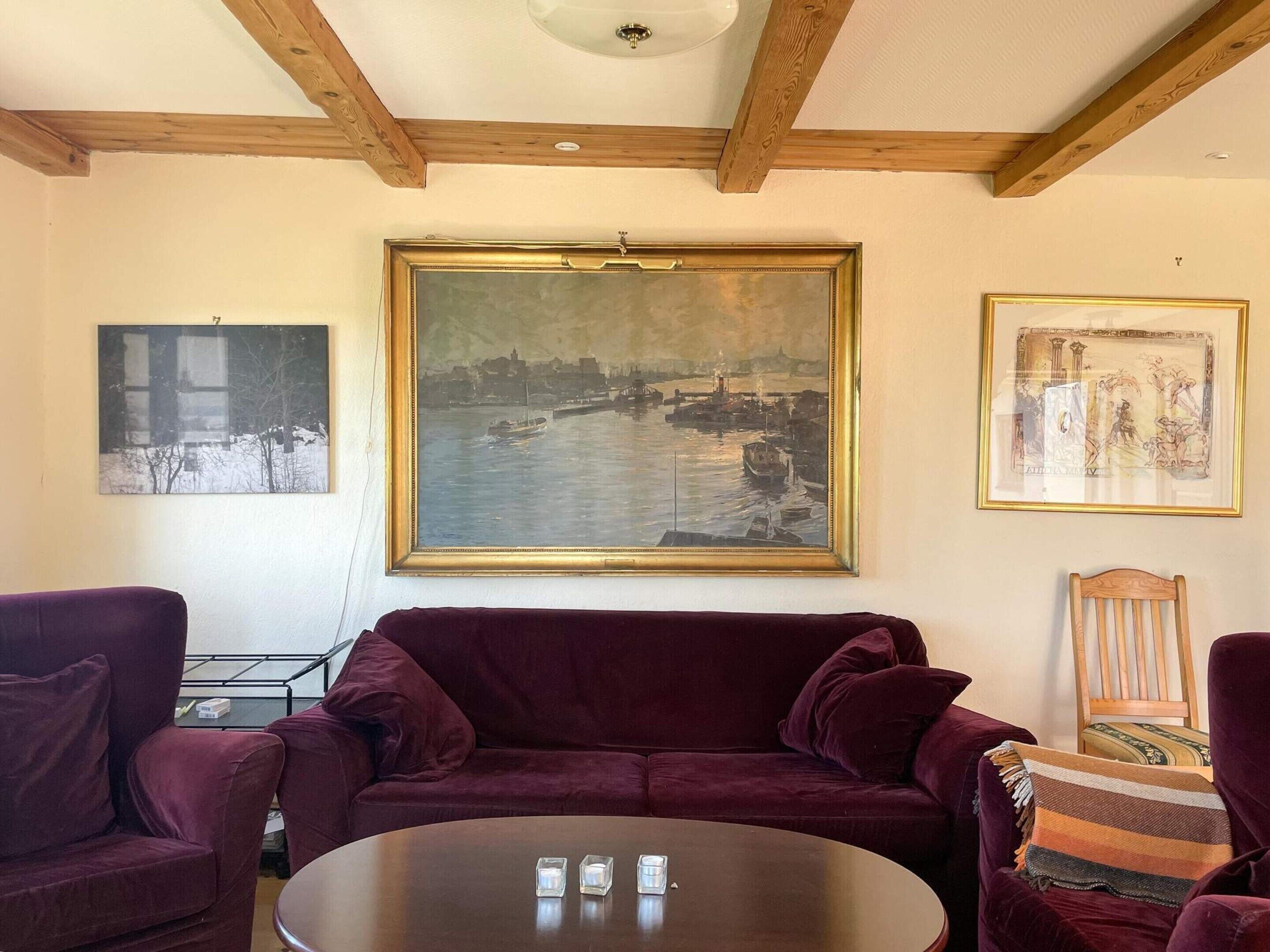 Ein Wohnzimmer mit einem großen Gemälde, einem runden Couchtisch und einem violetten Sofa.