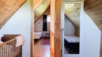 Une chambre avec un plafond en pente, une porte en bois, un lit et une petite table de chevet.