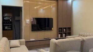 Ein modernes Wohnzimmer mit Flachbildfernseher, einer integrierten Unterhaltungsecke und einer Sitzecke mit Sofas und einem Tisch.