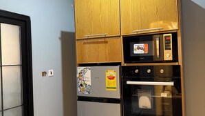 Eine kompakte Küche mit integriertem Kühlschrank, Backofen und Mikrowelle.