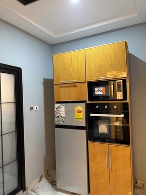 Eine kompakte Küche mit integriertem Kühlschrank, Backofen und Mikrowelle.