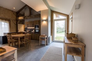 A modern kitchen with wooden beams, a dining area with a table and chairs, and a large window providing a view of the outdoors. - CHAURRON 2 - ARTHEZ D'ARMAGNAC (ARTHEZ D'ARMAGNAC)