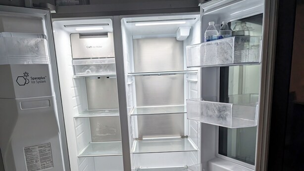 A refrigerator with multiple shelves and a freezer compartment, both empty.
