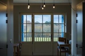 A room with a large window, a door, a table, and hanging lights. - PASQUET 2 - ARTHEZ D'ARMAGNAC (ARTHEZ D'ARMAGNAC)