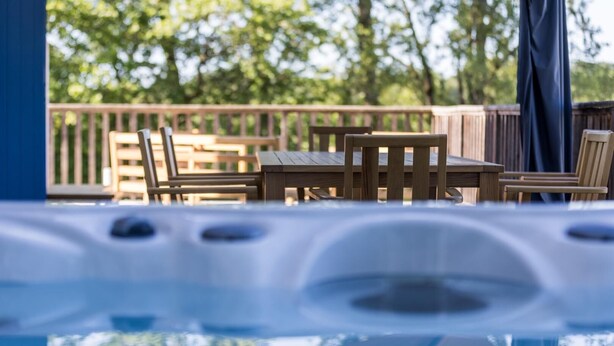Ein Whirlpool mit Holzterrasse und Gartenmöbeln.