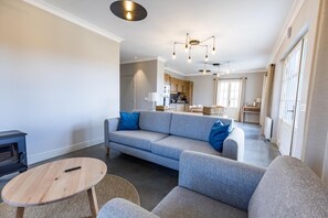 A modern living room with a grey sofa, a round wooden table, and a kitchen in the background. - PASQUET 2 - ARTHEZ D'ARMAGNAC (ARTHEZ D'ARMAGNAC)