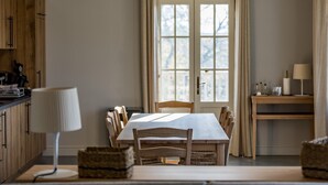 Ein Essbereich mit Tisch, Stühlen, einer Lampe und einem Fenster mit Vorhängen.